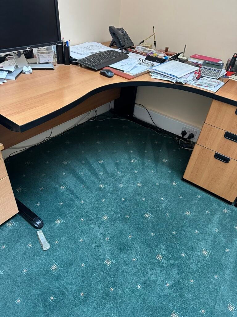 Freshly cleaned green patterned office carpet showing vacuum stroke marks under an office desk in Dublinv