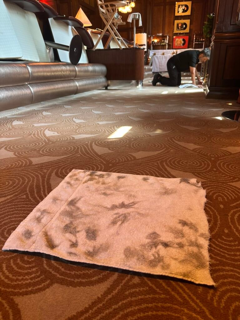 Carpet cleaning technician spot treating restaurant carpet with soiled towel showing extracted dirt