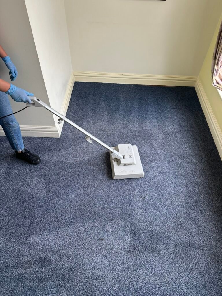 Technician using rotary carpet cleaning machine on blue hotel room carpet
