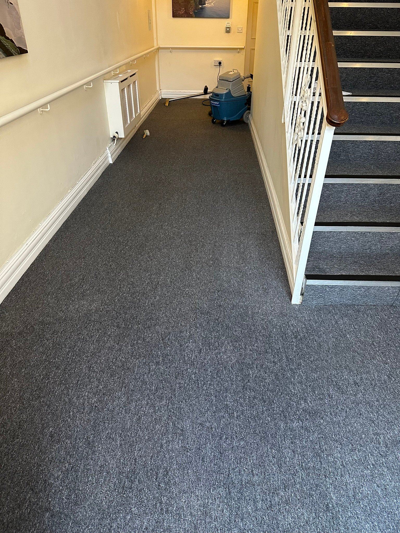 Professional carpet extraction cleaning machine set up in hotel corridor near staircase
