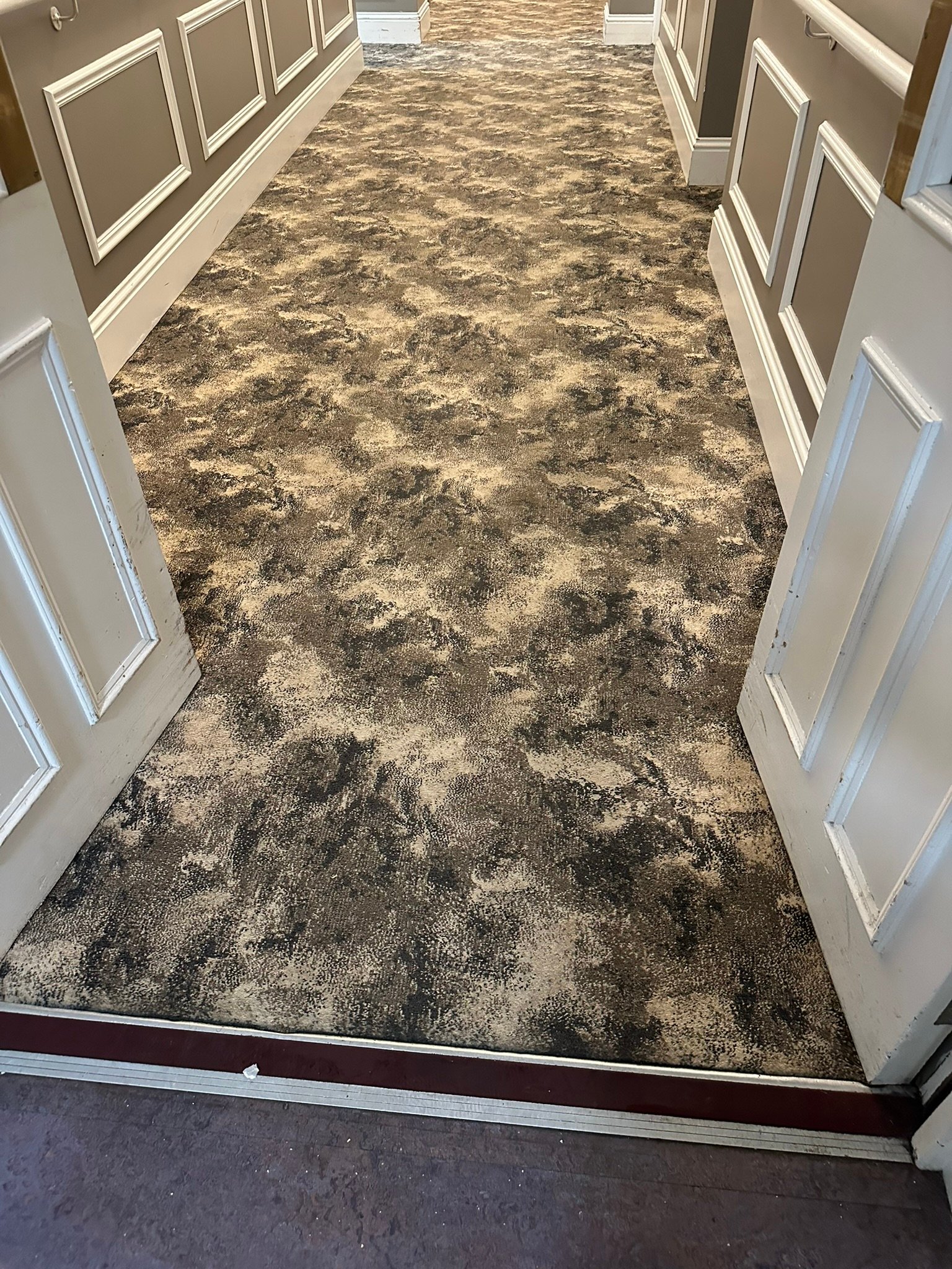 Hotel Corridor Carpet Deep Cleaning – Long Hallway Deep cleaned patterned carpet in a long hotel corridor with wood paneled walls